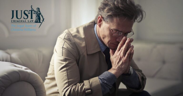 Man in beige coat and glasses sitting on couch, appearing deep in thought; law firm logo visible.