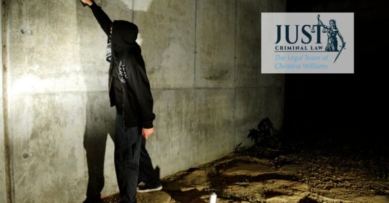 Person in dark clothing spray painting on a concrete wall at night, logo of Just Criminal Law in the corner.