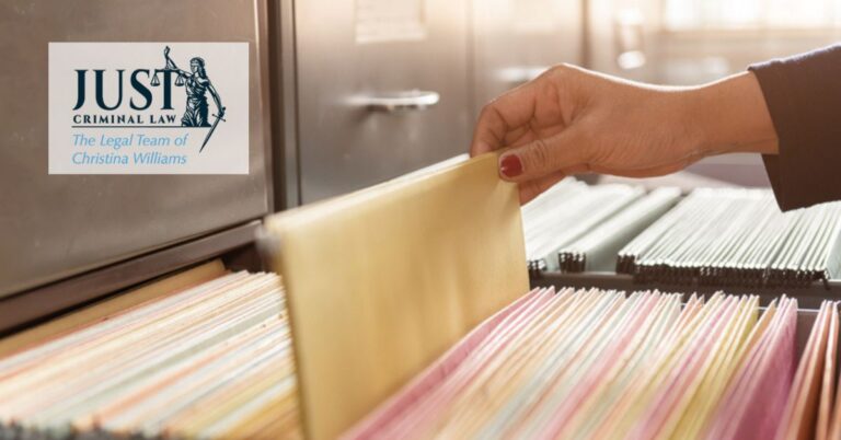 Hand with red nail polish retrieving a file folder from a filing cabinet, Just Criminal Law logo visible.