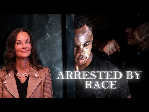 Split-screen image with a woman in a brown jacket on the left and a man with clenched fists on the right, overlaid with the text "ARRESTED BY RACE.