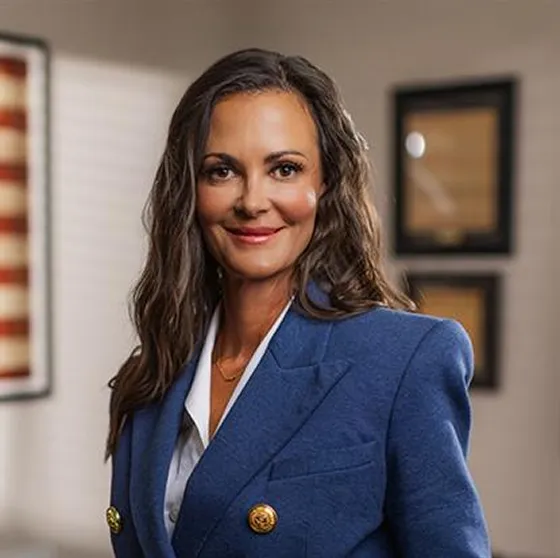 Professional portrait of a woman with long brown hair wearing a blue blazer.