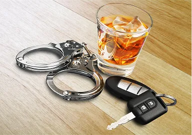 Glass of whiskey with ice, metal handcuffs, and a black car key on wooden surface.