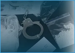 Handcuffs, plastic bags containing white powder and small beads, and an envelope on a dark surface.