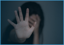 Blurred person with dark hair covering face, hand extended forward in stop gesture.