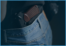 Close-up of a handgun holstered in the waistband of blue denim jeans.