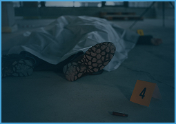 Crime scene with a covered body on the floor, evidence marker, and bullet casing.