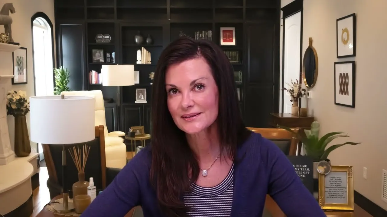 Woman with long dark hair in a blue cardigan seated in a modern home office.