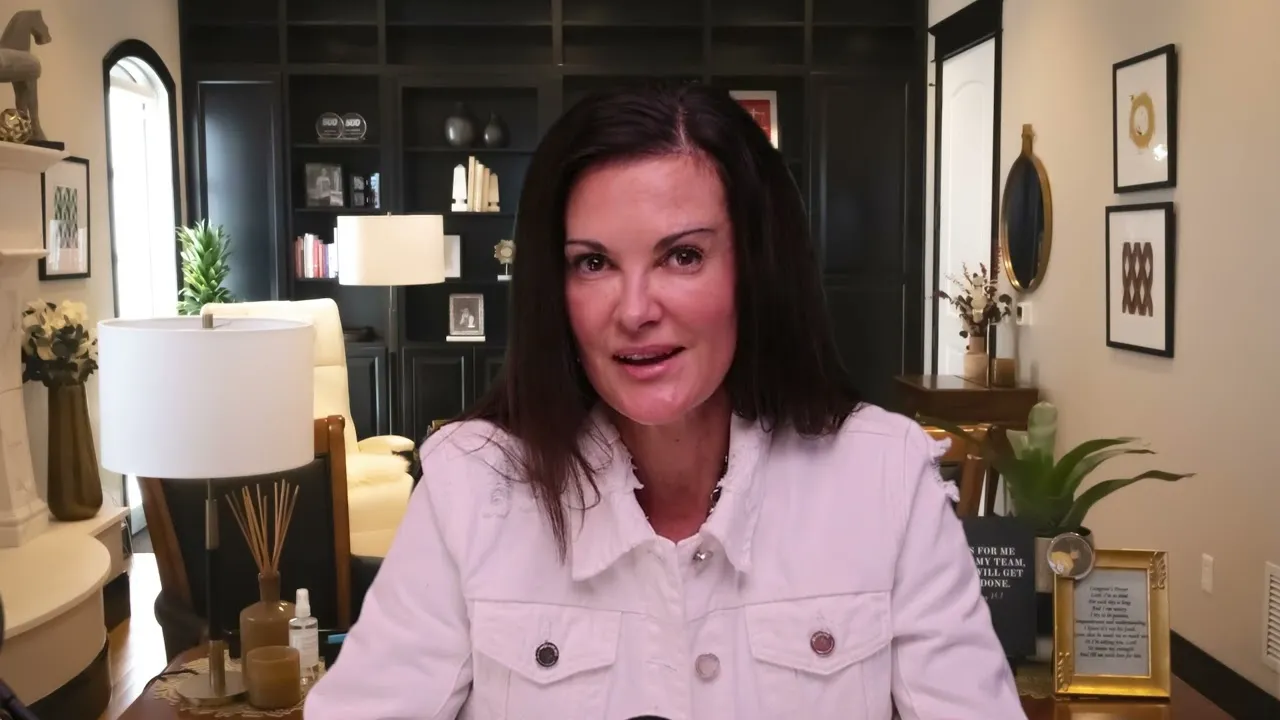 Professional woman with dark hair wearing a white jacket, seated in a well-decorated office.