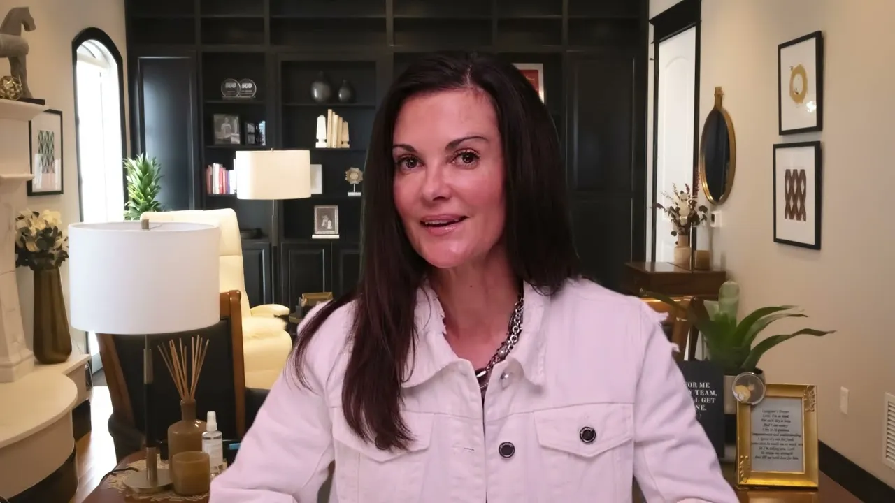 Professional woman with dark hair wearing a white jacket in a modern, well-lit office.