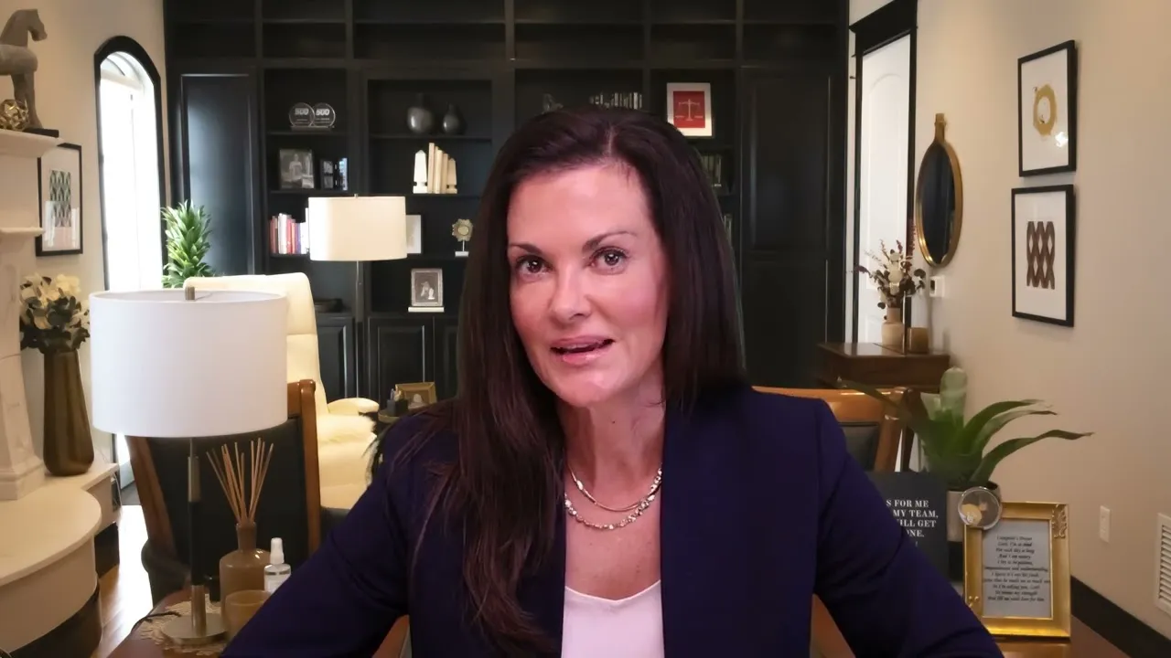 Professional woman with long dark hair speaking in a well-lit office with dark bookshelves and decorative items.