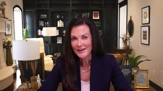 Woman with dark hair speaking in a well-lit, professionally decorated home office.
