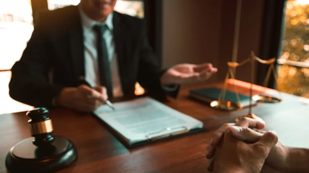 Professional legal consultation scene with lawyer, client, gavel, and scales of justice.