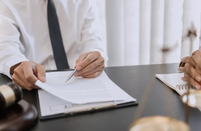 Two individuals in formal attire reviewing a document on a desk with legal symbols.