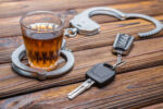 Concept drunkenness driving. Handcuffs, a glass of alcohol, car keys.