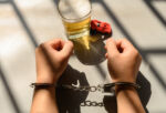 arrested drunk driver in a jail with handcuffs