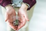Drug possession in Wyoming - Cuffed hands holding marijuana