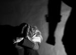Woman covering her face with the shadow of a mans fist on the wall